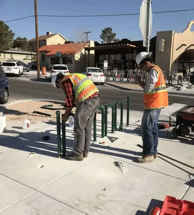 man in construction outfit installing bike lock railings img